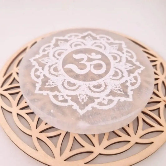 Plaque Sélénite Om posée sur une fleur de vie 